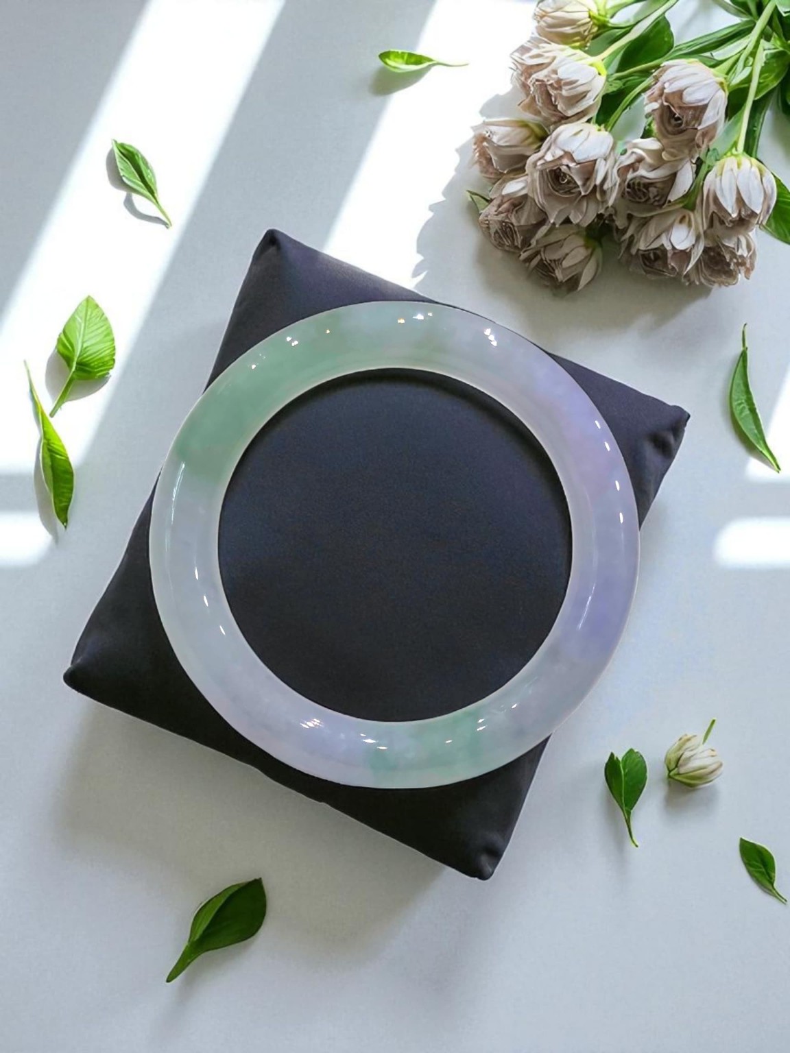 Natural jadeite bangle showing lavender green and icy tones under light